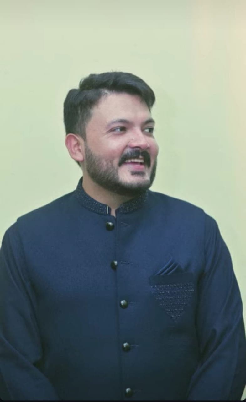 An elegant portrait of a man against a rustic Pakistani landscape.